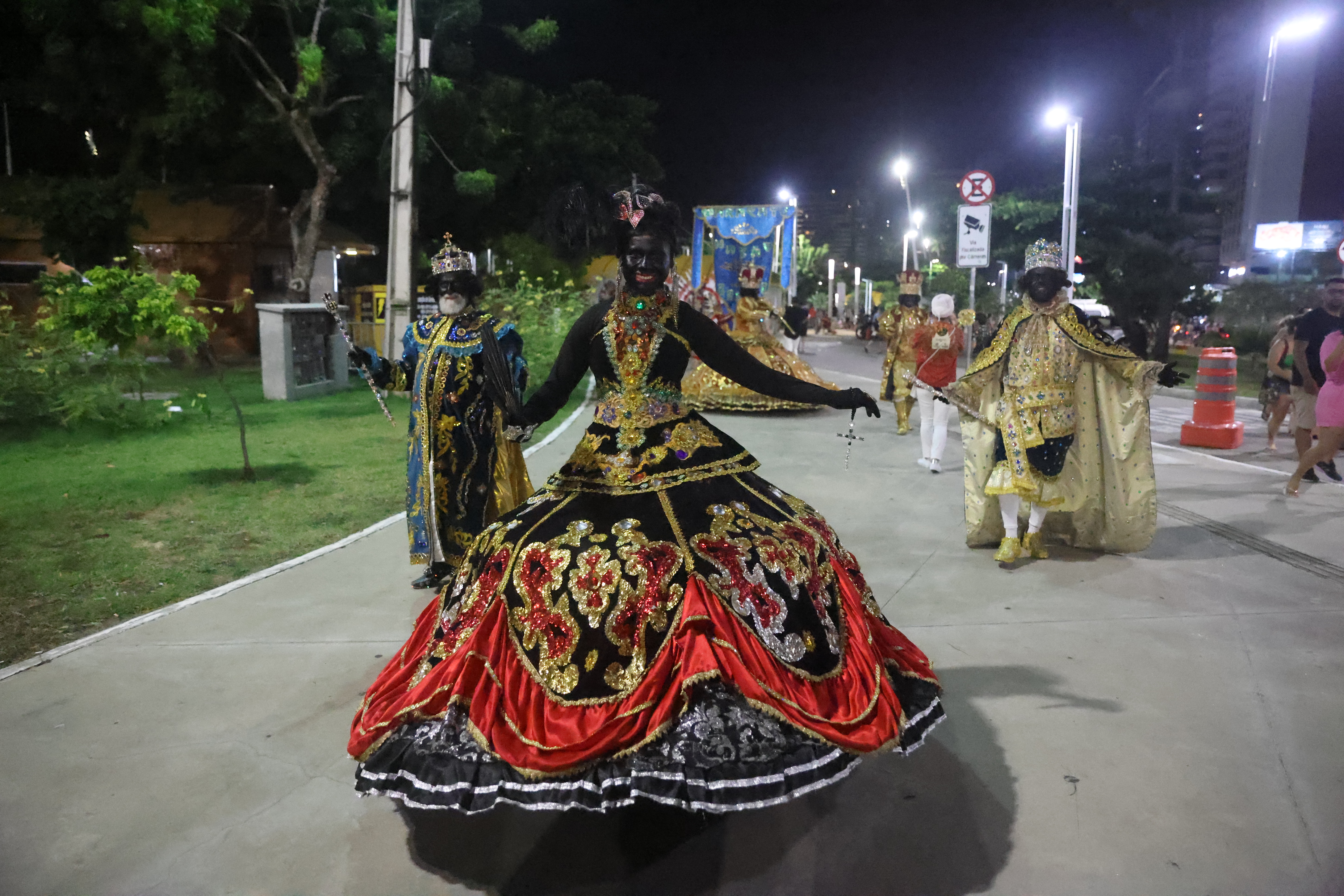 rainha do maracatu desfilando, como roupas com detalhes dourados e vermelhos